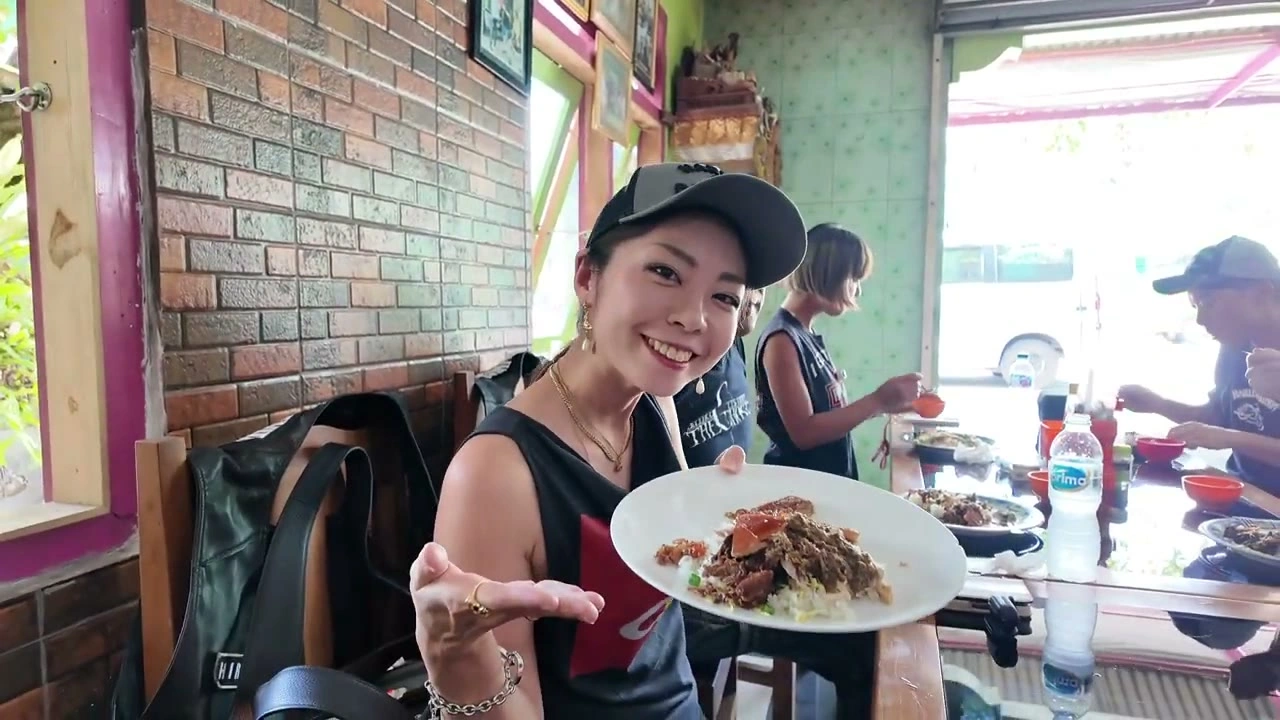 料理の皿を見せて笑う女性メンバー｜2025年3月 バリ島ハーレーツーリング — TEAM THE GHOST West Bali
