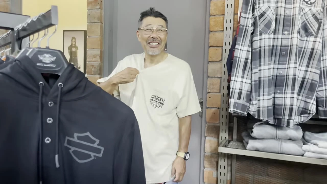 パーカーを手に白シャツの男性が笑顔｜2025年8月 バリ島ハーレーツーリング — TEAM THE GHOST West Bali