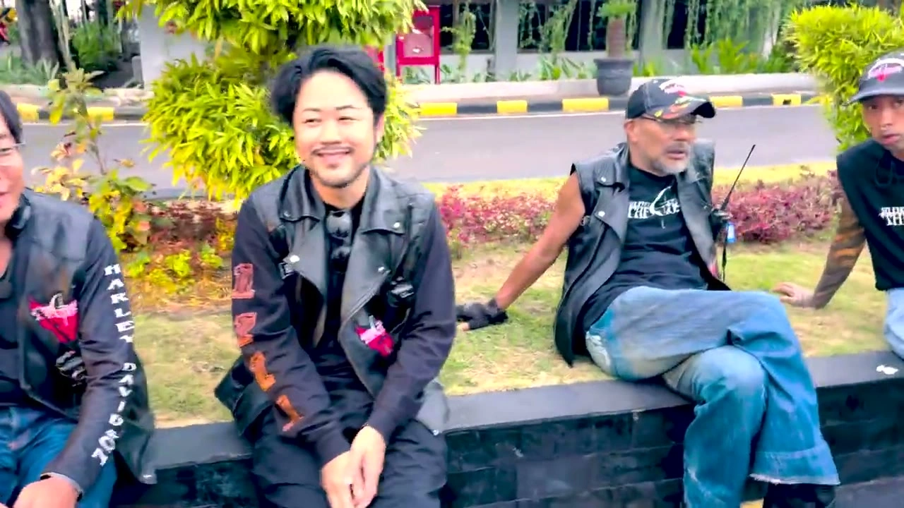 縁石に腰かけて笑う若者｜2025年9月 バリ島ハーレーツーリング — TEAM THE GHOST West Bali