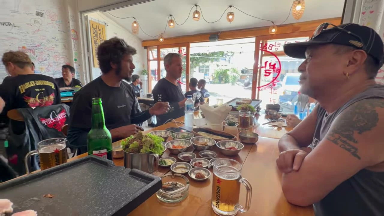 バーでメンバー談笑（タトゥーの腕）｜2026年3月 バリ島ハーレーツーリング — TEAM THE GHOST West Bali
