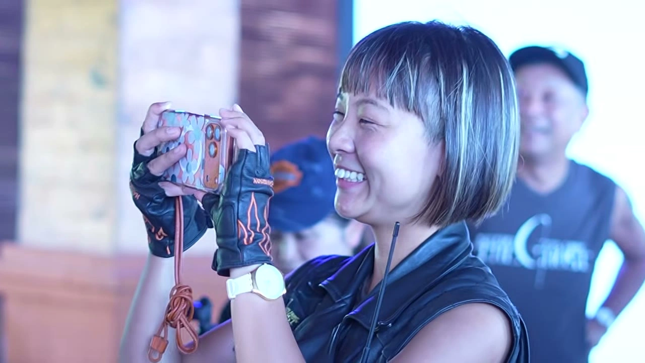 ボブヘアの女性が笑顔でカメラを構える（GHOSTベスト）｜2026年5月 バリ島ハーレーツーリング — TEAM THE GHOST West Bali