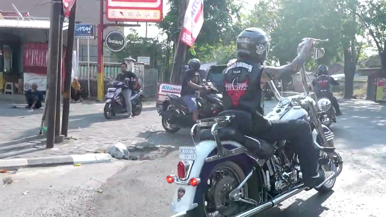 街角でバイクにまたがり手を挙げる｜2026年7月 バリ島ハーレーツーリング — TEAM THE GHOST West Bali