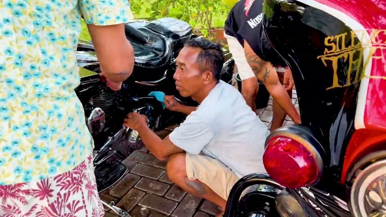 しゃがみ込んで愛車を磨く｜2026年7月 バリ島ハーレーツーリング — TEAM THE GHOST West Bali