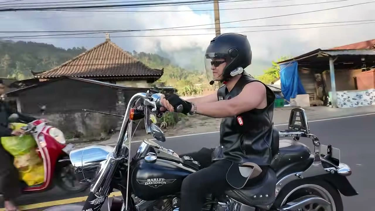 走りながらカメラに指差して応えるライダー｜2026年8月 バリ島ハーレーツーリング — TEAM THE GHOST West Bali