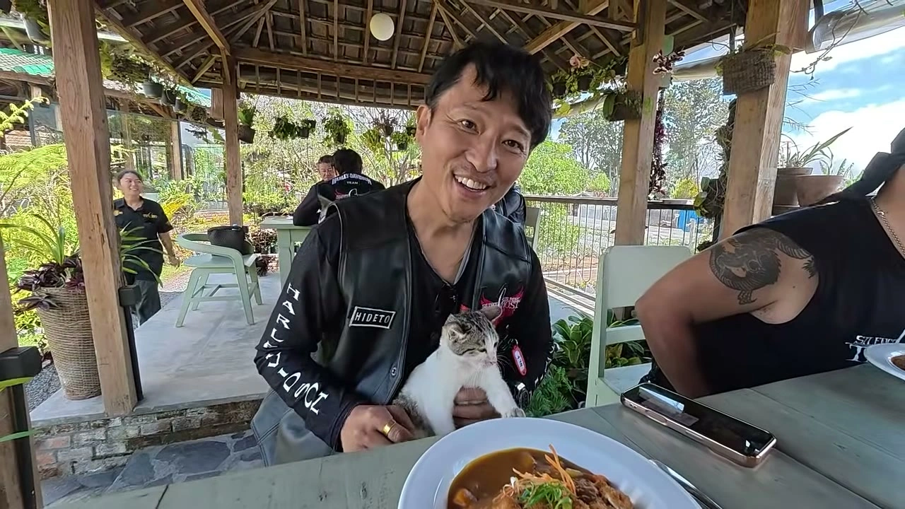 猫を膝に乗せて食事するメンバーの笑顔｜2026年8月 バリ島ハーレーツーリング — TEAM THE GHOST West Bali
