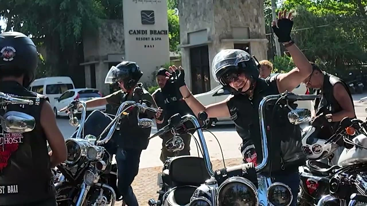 「CANDI BEACH」の看板の前、手を挙げて出発を待つ｜2026年9月 バリ島ハーレーツーリング — TEAM THE GHOST West Bali