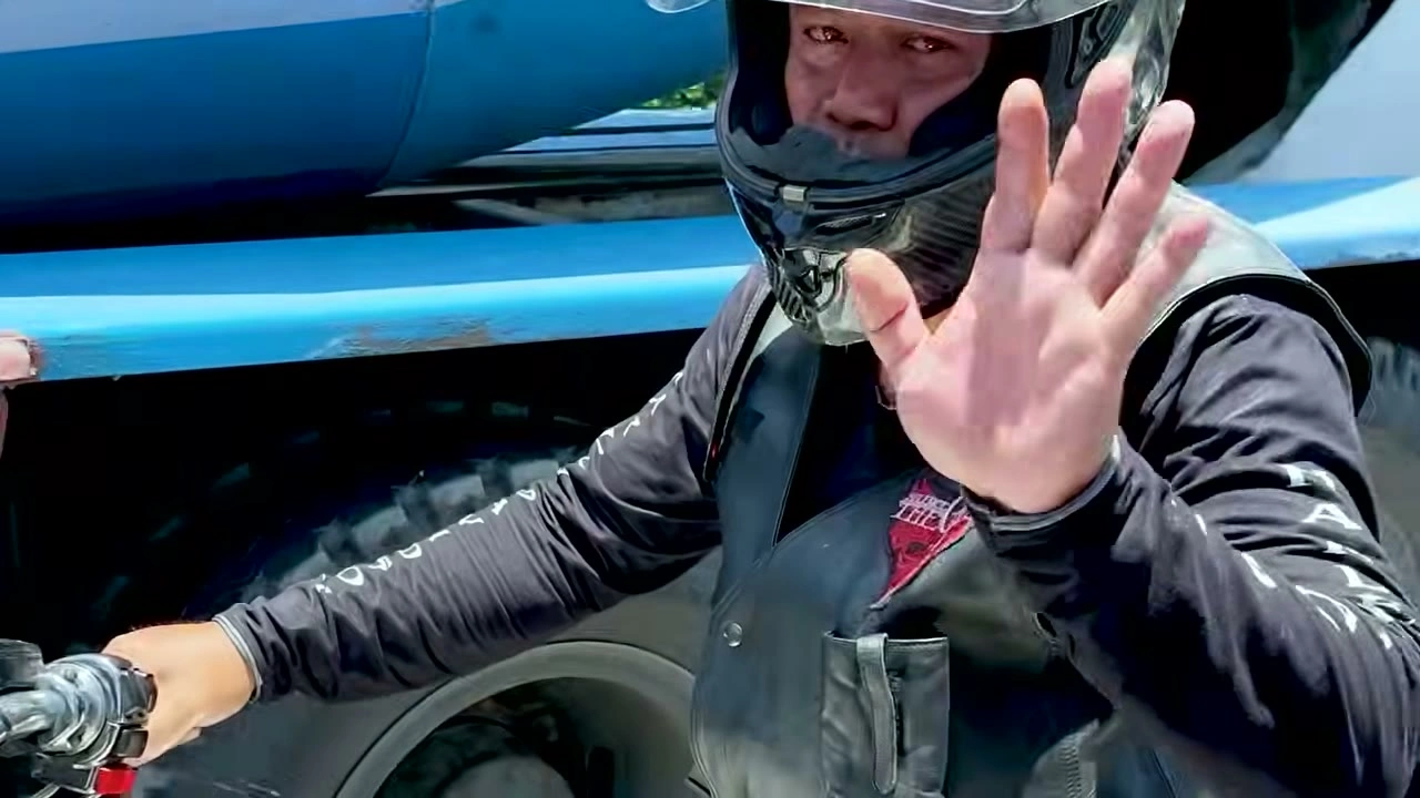 走り出す前、手を振ってカメラに挨拶するライダー｜2026年10月 バリ島ハーレーツーリング — TEAM THE GHOST West Bali