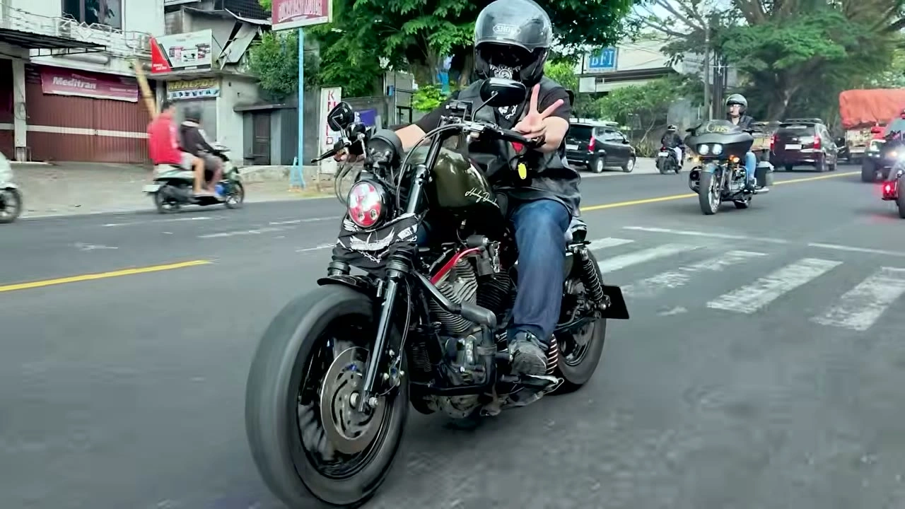 横断歩道の先から、ピースサインで走ってくるライダー｜2026年10月 バリ島ハーレーツーリング — TEAM THE GHOST West Bali