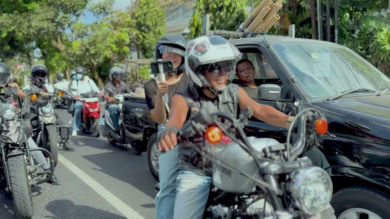 渋滞の中、自撮り棒を手に笑顔の二人乗り｜2026年10月 バリ島ハーレーツーリング — TEAM THE GHOST West Bali